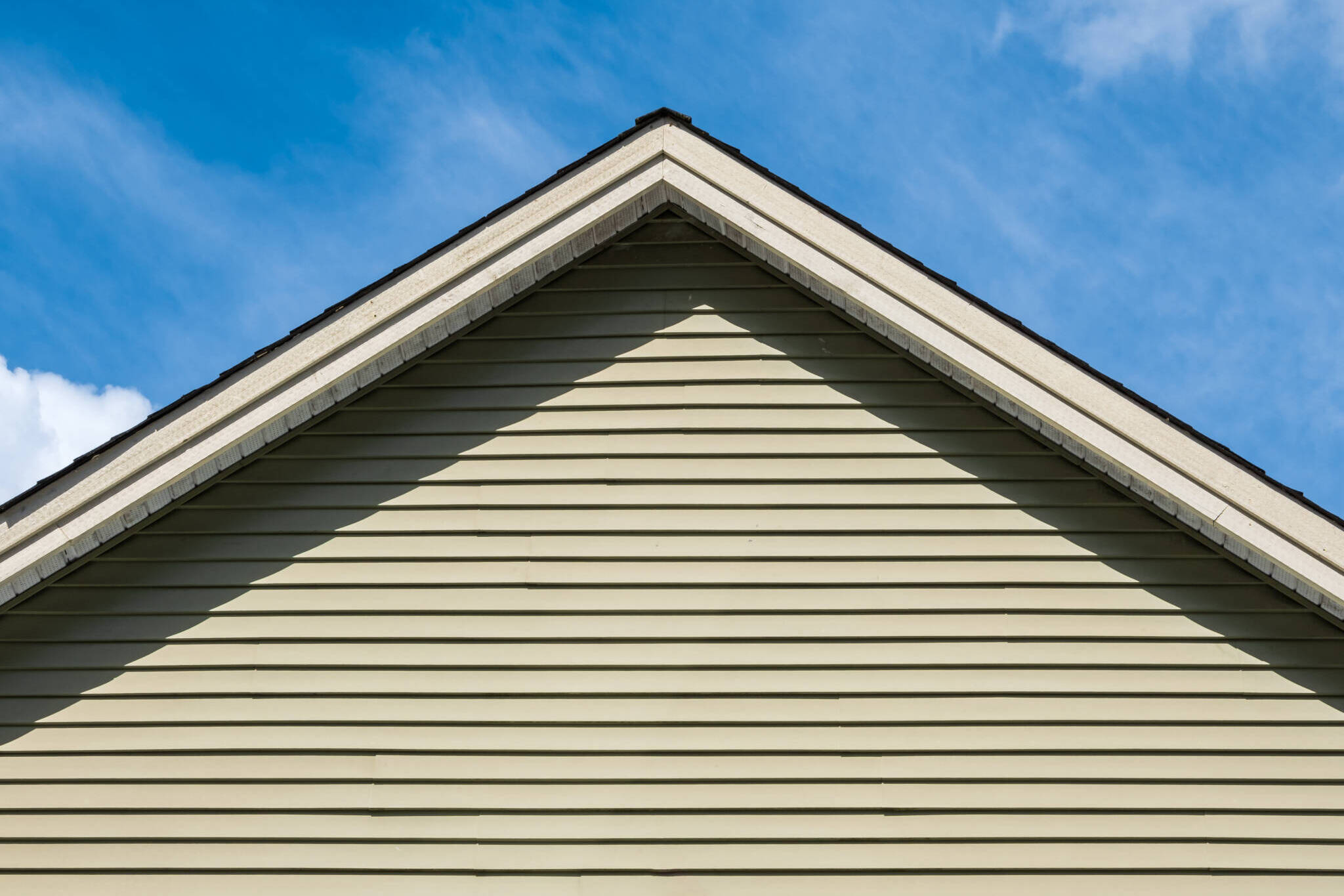 Top Of House. Triangle House Top In The Blue Sky Background. Gray Vinyl Wooden Siding Panel On The House.
